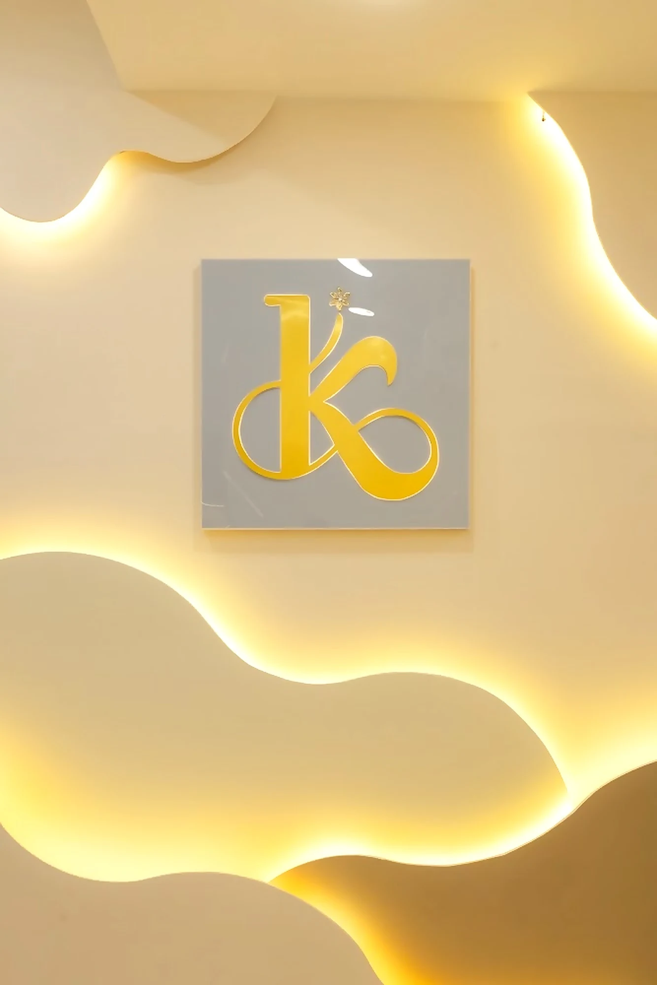 Ishita Kapoor gold K monogram on a softly backlit studio wall